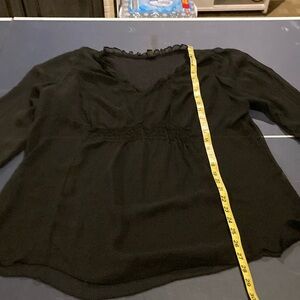 A completely see-through blouse with ruffled collar and bunching in front.